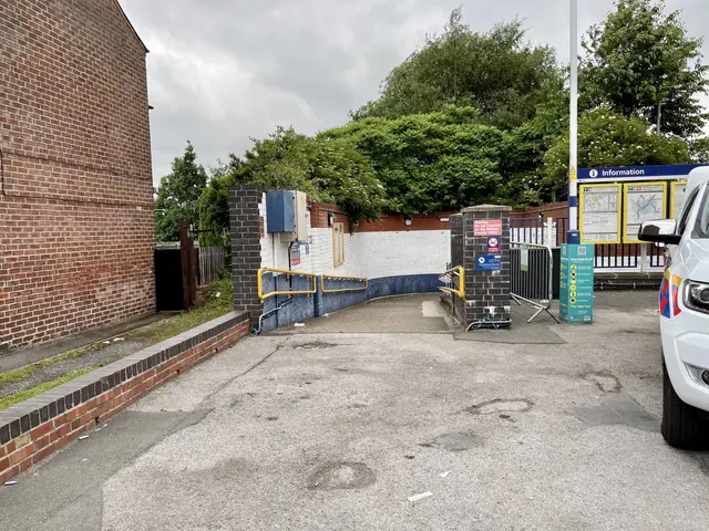 The image shows a police car parked in front of a brick building, with a pole in the foreground and...