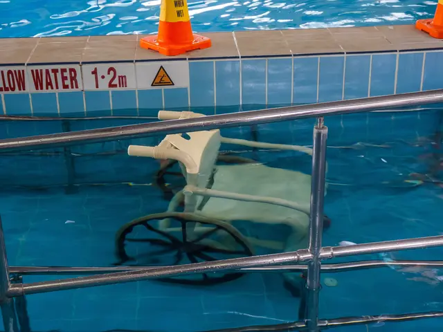 The image shows a swimming pool with a chair in the middle of it, surrounded by safety cones and a...