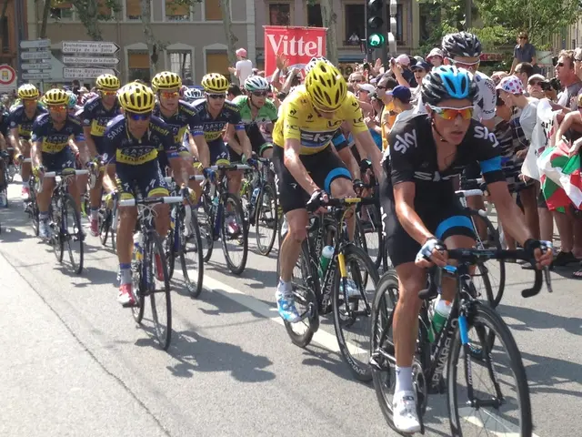 The image shows a group of people riding bicycles down a street, with a crowd of people standing on...