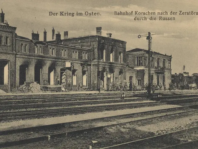 The image shows an old black and white photo of a train station with railway tracks, buildings,...