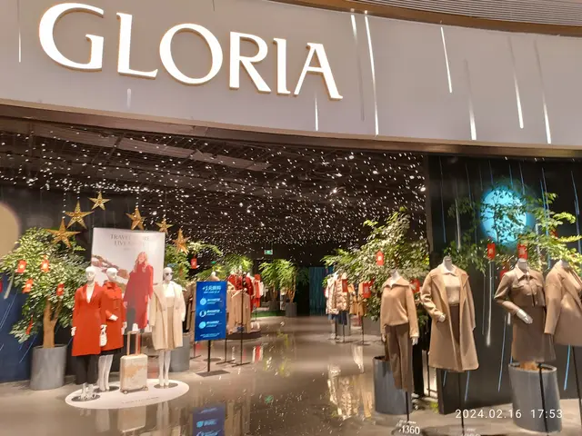 The image shows a Gloria clothing store in Hong Kong, with mannequins wearing dresses, plants,...