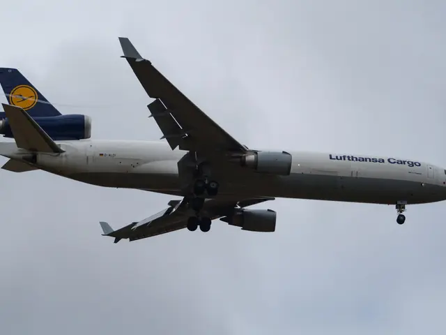 The image shows a Lufthansa Cargo Boeing 777-300ER in flight, with its wings spread wide and its...