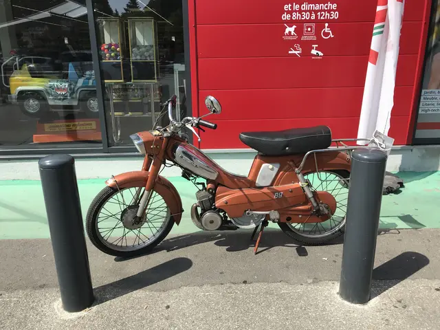 The image shows an orange moped parked in front of a red building with glass walls. On the right...