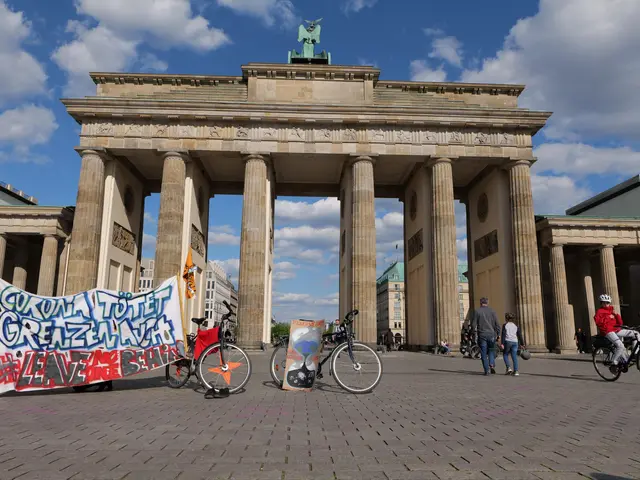 The image shows a group of people riding bicycles in front of the Brandenburg Gate in Berlin,...