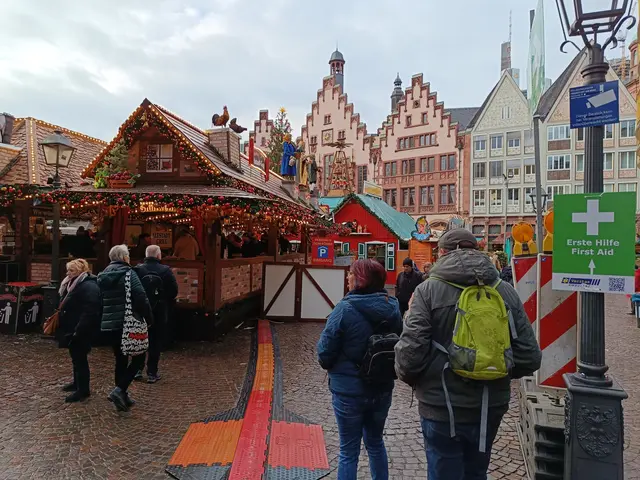 The image shows a group of people walking down a cobblestone street next to a Christmas market in...