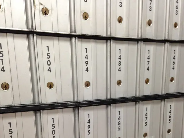 The image shows a close up of a bunch of mailboxes stacked on top of each other. The mailboxes are...