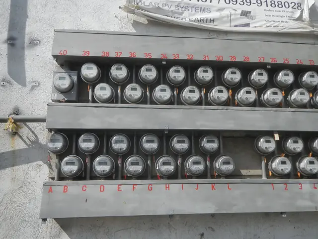 The image shows a close up of an electric meter on the side of a building. The meter is mounted on...