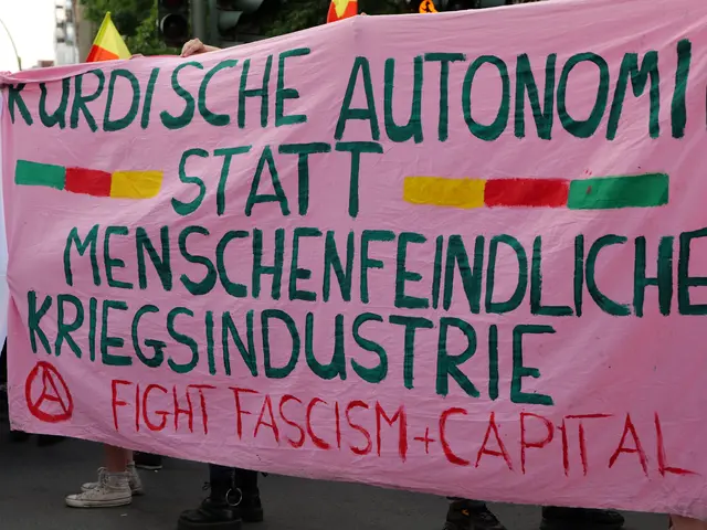 The image shows a group of people standing on the road, holding a pink banner that reads "Kurdische...