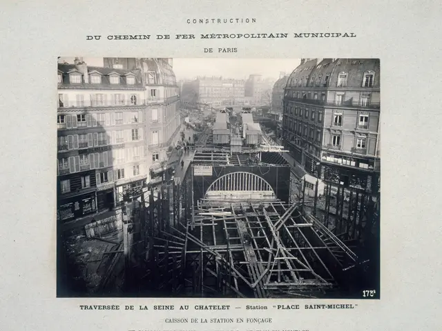 The image shows a black and white photo of a city street with a bridge under construction. There...