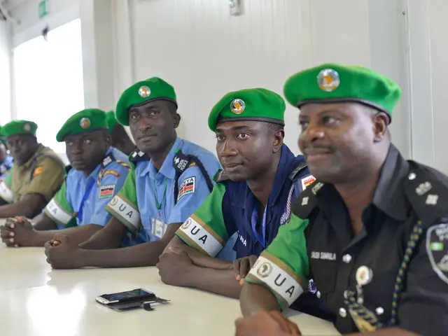 The image shows a group of police officers sitting at a table in a room with a wall in the...