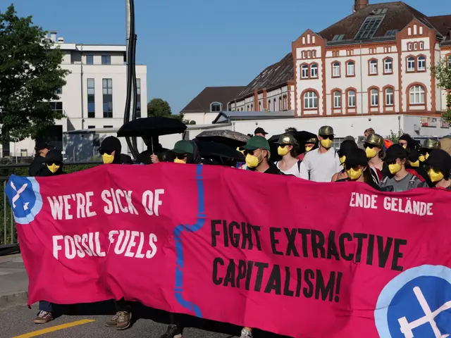 The image shows a group of people wearing masks and holding a pink banner that reads "We're Sick of...