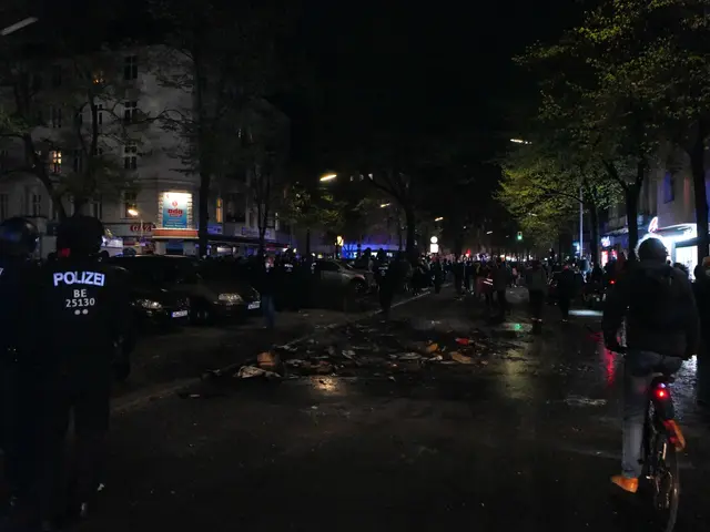 The image shows a group of police officers standing on the side of a street at night. There is a...