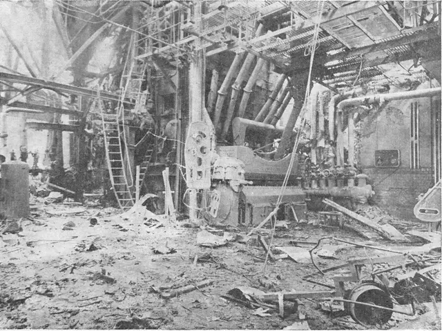 The image shows a black and white photo of a factory with a lot of debris on the ground, including...
