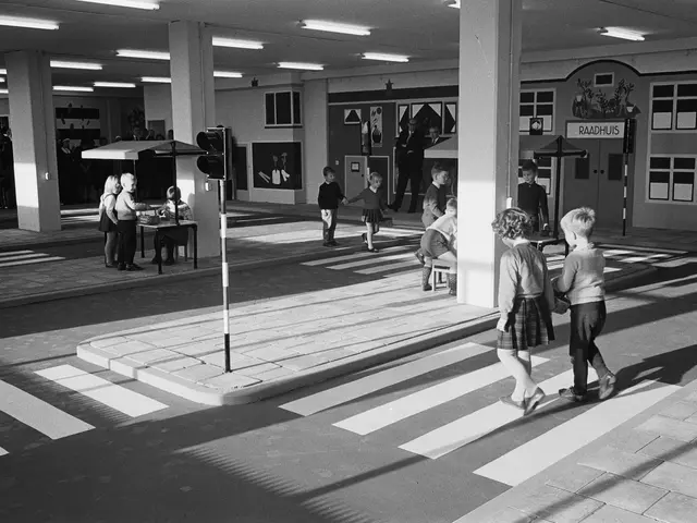 The image shows a black and white photo of a group of children crossing the street at a crosswalk....