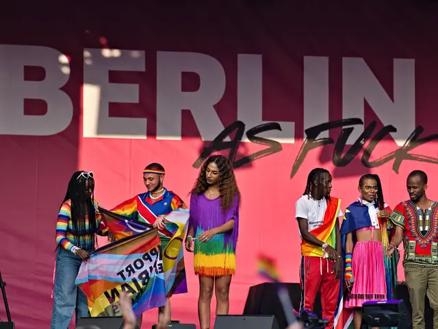 The image shows a group of people standing on top of a stage, with a woman holding a flag in the...