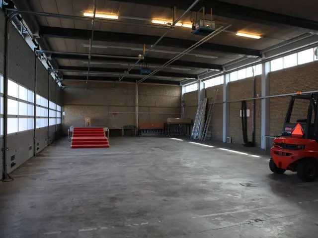 The image shows a large warehouse with a forklift parked inside of it. On the right side of the...