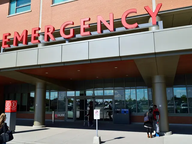 The image shows a group of people walking in front of an emergency building with glass walls and...