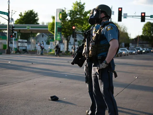 The image shows a police officer wearing a gas mask standing on the side of the road. He is wearing...
