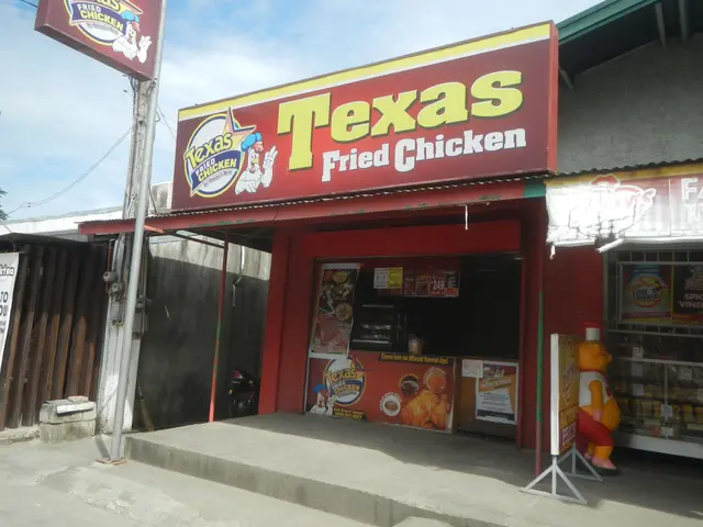 The image shows a Texas Fried Chicken restaurant on the corner of a street. There is a board with...