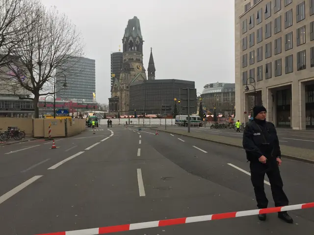 The image shows a police officer standing in the middle of a street in Berlin, Germany. He is...