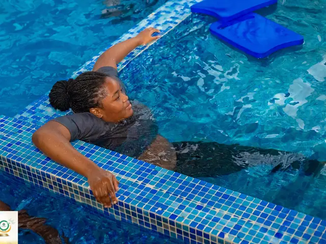 The image shows a woman in a swimming pool with her arms outstretched, wearing a t-shirt and...