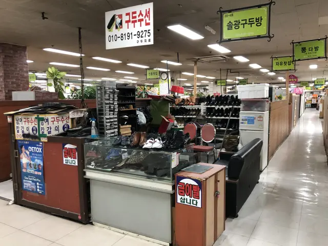 The image shows a store filled with lots of different types of shoes, arranged in racks and on the...