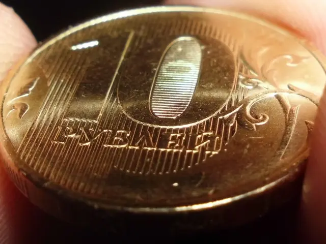 The image shows a person holding a gold coin in their hand against a dark background.