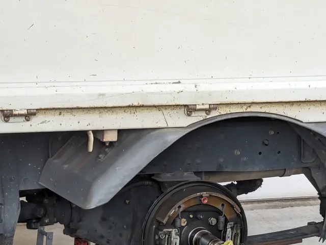 The image shows a truck parked in a garage with a yellow cloth draped over it. On the ground in...