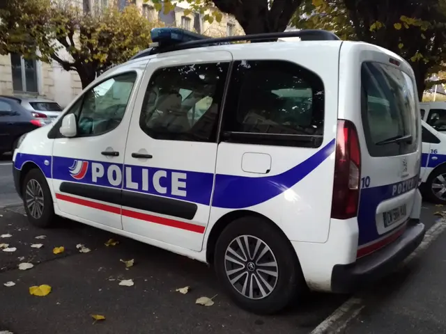 The image shows a police van parked on the side of a street, surrounded by buildings with windows,...