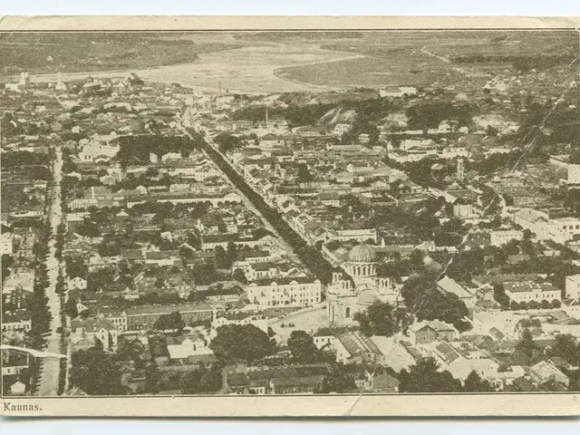 The image shows an old black and white photo of a city with buildings, trees, roads, and water. At...