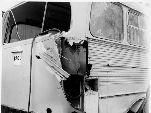 The image shows a black and white photo of a bus that has been damaged by a car accident. The bus...