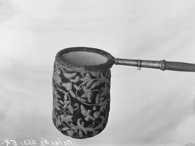 The image shows a black and white photo of a yerba mate cup with a wooden handle. The cup is...