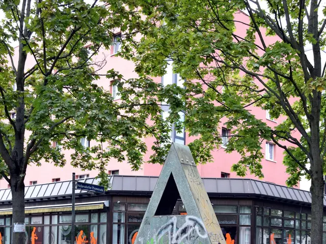 The image shows a metal sculpture in the middle of a park with graffiti on it, surrounded by trees,...