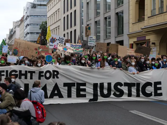 The image shows a large group of people walking down a street, holding a banner that reads "Fight...