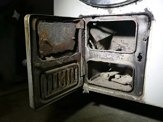 The image shows an old stove with its door open in a dark room. The stove is white in color and...