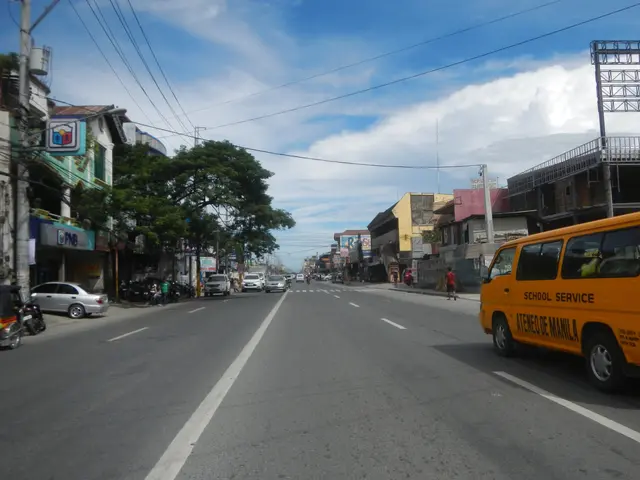 The image shows a yellow school bus driving down a street lined with tall buildings on either side....