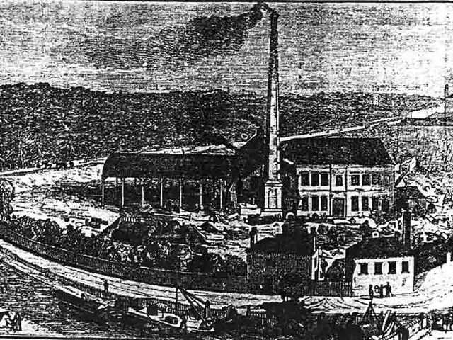 The image shows a black and white drawing of a factory in the middle of a field, with a few...
