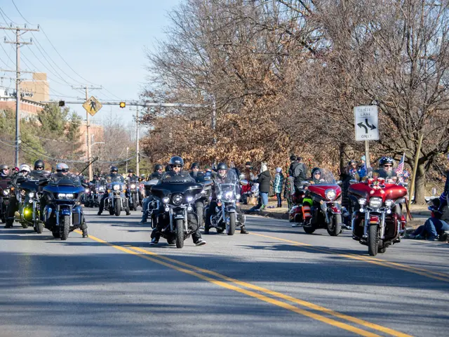 The image shows a group of people riding motorcycles down a street lined with electric poles with...