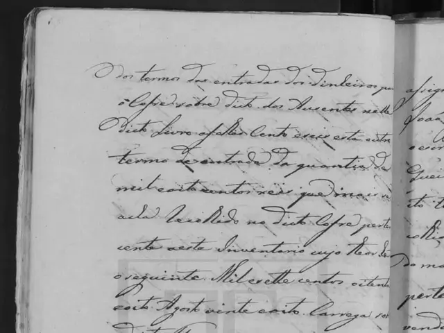 The image shows an open book with handwriting on it in black and white. The text on the book reads...