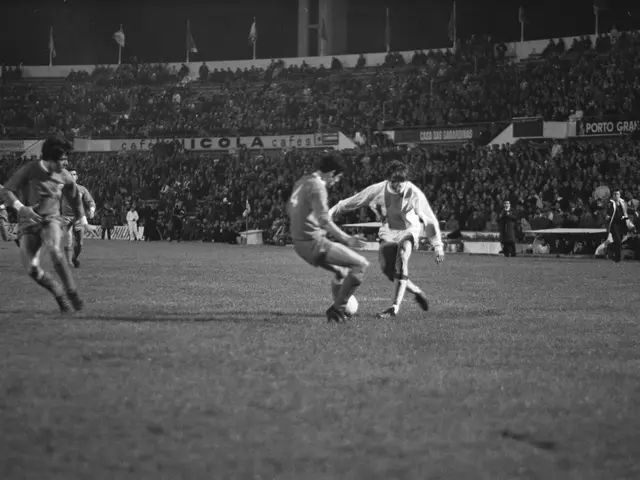The image shows a group of men playing soccer on a field in a stadium, with a crowd of people...