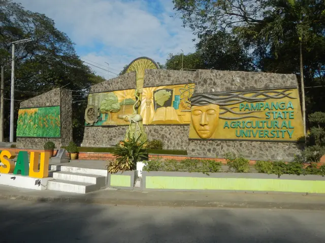 The image shows the entrance to Pampanga State Agricultural University, with a wall adorned with...