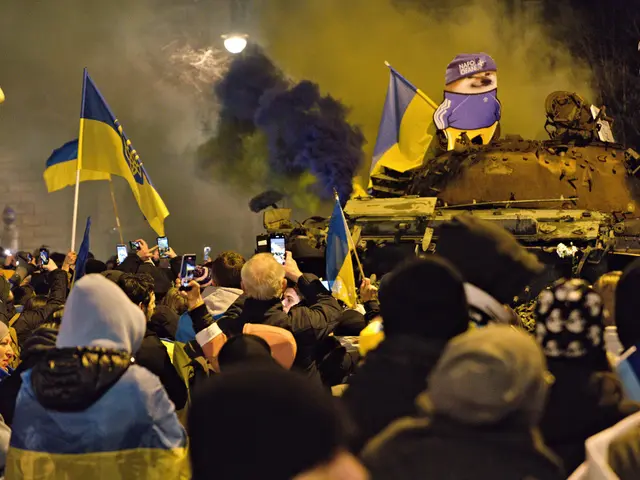 The image shows a crowd of people standing in front of a tank, some of them holding flags and...