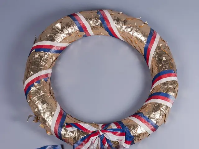 The image shows a wreath made out of gold foil with red, white and blue ribbons tied around it,...
