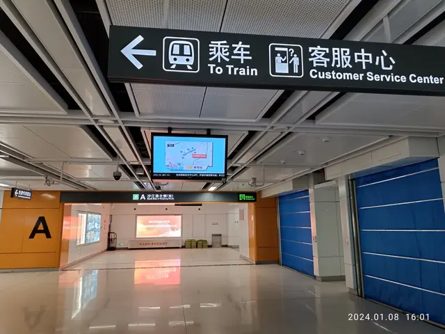 The image shows an inside view of a train station with a sign that reads "To Train Customer Service...