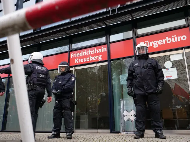 The image shows a group of police officers standing in front of a building with glass walls and...
