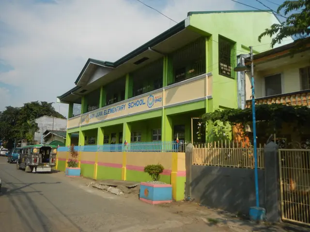 The image shows a school building with a green and yellow facade on the side of a street,...