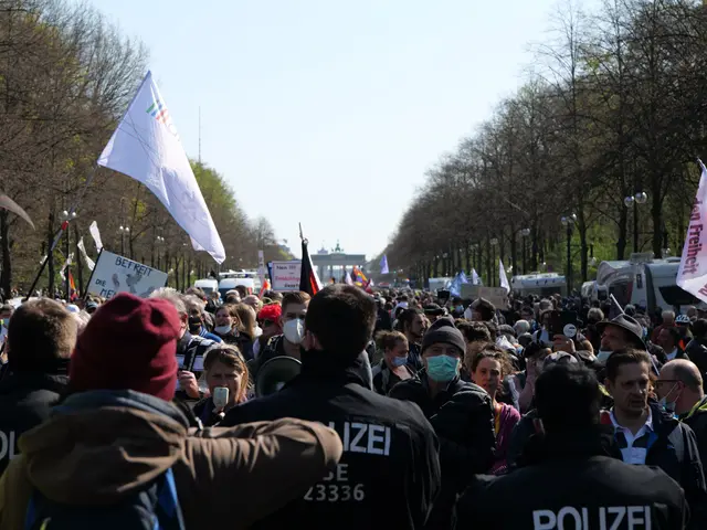 The image shows a large group of people standing in front of a crowd of police officers, some of...