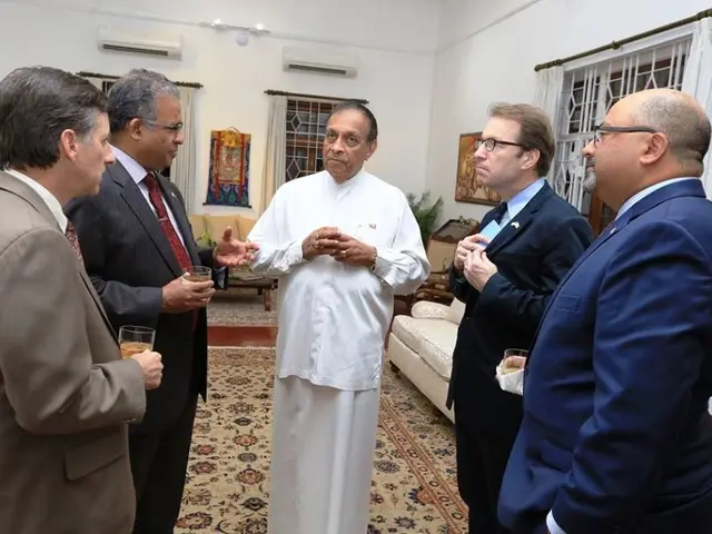 The image shows a group of men standing around each other in a room, with some of them holding...