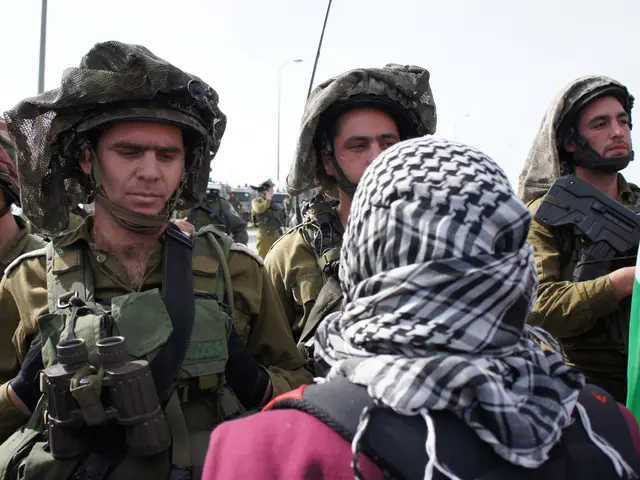The image shows a group of Israeli soldiers standing next to each other in front of a crowd. They...