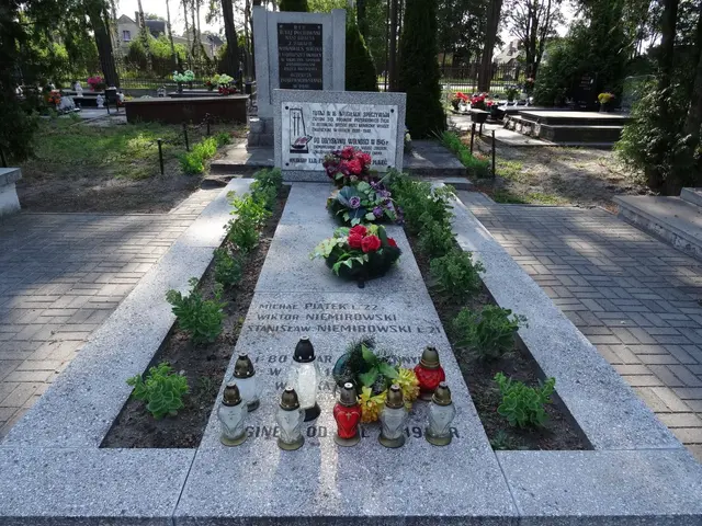 The image shows a memorial in the middle of a park with flowers and candles on it, surrounded by...